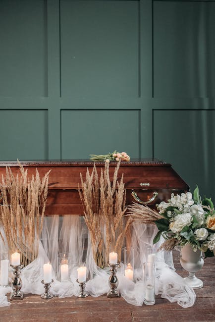A floral arrangement featuring a variety of white and blush roses, complemented by lush green foliage, placed in a classic white ceramic vase. The bouquet is positioned beside a polished wooden piano,