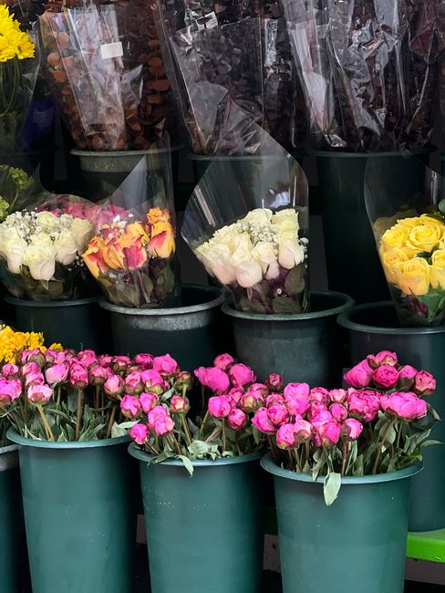 A display of fresh flower bouquets and floral arrangements at Bexley Florist for flower delivery, positioned in green plastic buckets. The arrangements include white roses and multicolored roses in pi